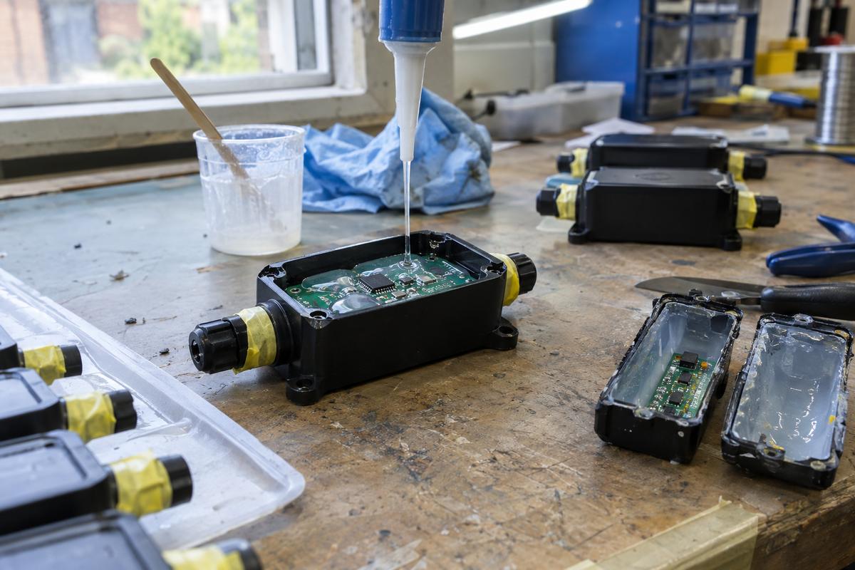 Part-filled silicone housing around electronics with masked connectors kept clear