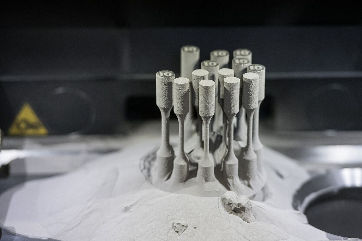 Metal parts emerging from the powder bed after a DMLS build.