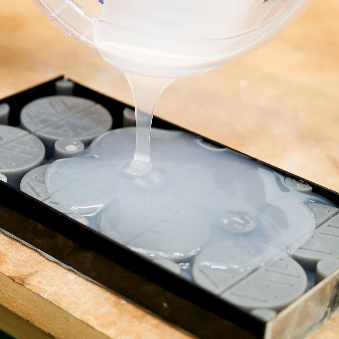 Pouring silicone over master patterns in a mould box.